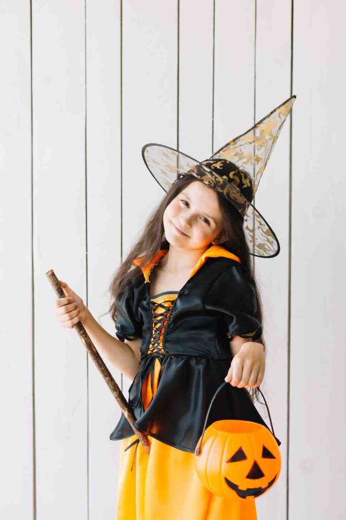 girl halloween costume with pumpkin basket posing studio
